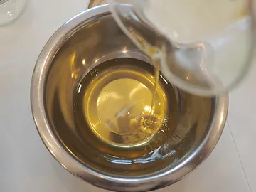 Oil is poured into a metal bowl.