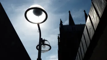 Street lamp glows, shadows of buildings in the background.