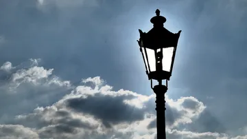 Straßenlaterne beleuchtet den Himmel bei Wolkenformationen.