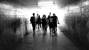 Gruppe von Menschen geht durch dunklen Tunnel ins Licht.
