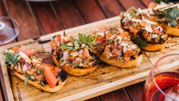 Geröstete Brotscheiben mit frischer Salsa auf Holzbrett.