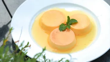 Dreier Pudding mit orangefarbener Soße und Minze.