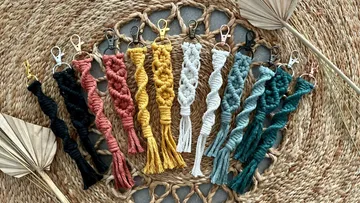 Macramé keychains hang on a woven surface.