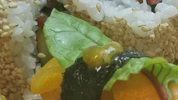 Sushi roll wrapped with fresh vegetables and seaweed.