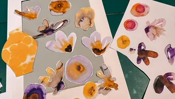 Paper flowers lie on a table for crafts.