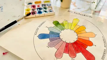Farbkreis mit Pinsel, auf kreativem Tisch mit Wasserfarben.