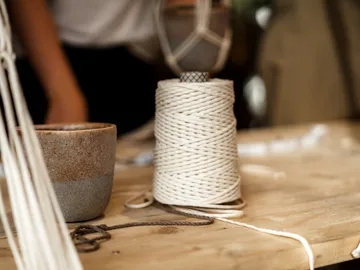 Schnurrolle auf Tisch neben einer Tasse, handwerkliche Umgebung.
