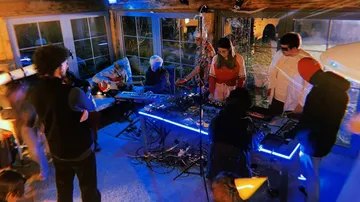 A group of people are playing electronic music in a room.