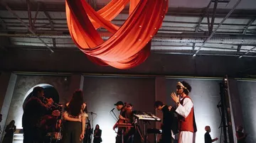 Ein rotes Tuch schwebt über einer Musikergruppe in einem Raum.