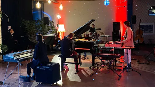 Musicians playing instruments in dimly lit room.