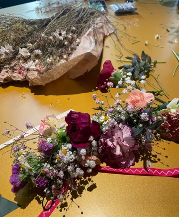 Blumenarrangement liegt auf einem goldenen Tisch, umgeben von Trockenblumen.