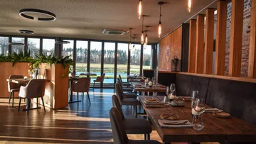 Elegant restaurant with tables, views of nature.