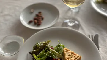 Ein Teller mit Salat und einer Quiche, daneben ein Getränk.