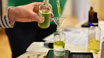 Hände verwenden Pipette, um Flüssigkeiten in Flaschen zu mischen.