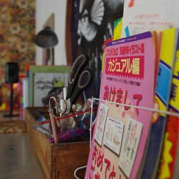 Schreibtisch mit Büchern und Schere in kreativer Umgebung.