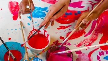 Paint over colors with brushes on a table.