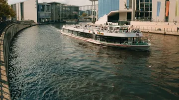 Ein Schiff fährt auf einem Fluss in einer Stadt.
