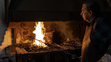 Ein Schmied arbeitet an einem Feuer im Amboss.