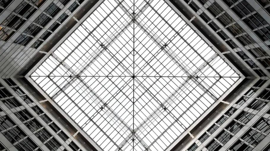 Grid-shaped glass roof over modern building structures in the courtyard.