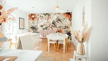 Helles Café mit blühendem Wanddesign und eleganten Tischen.