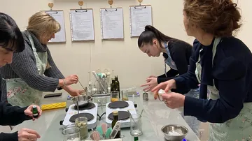 Vier Frauen bereiten an einem Tisch kosmetische Produkte vor.