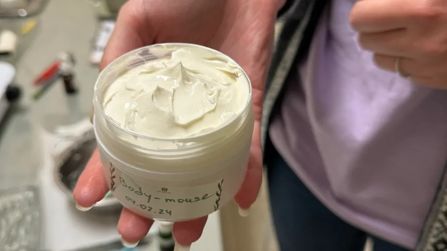 Eine Person hält eine Creme in einem Behälter.