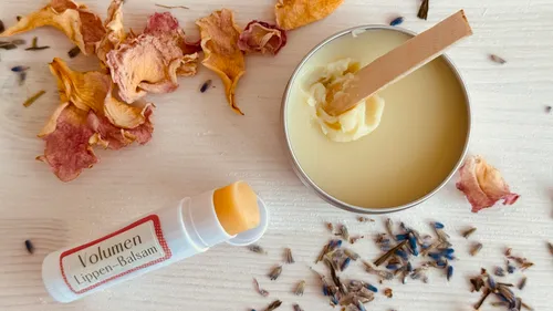 Lippenbalsam liegt neben einem offenen Behälter mit Cream.