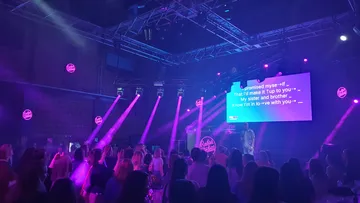 Crowd enjoying karaoke under purple lights.