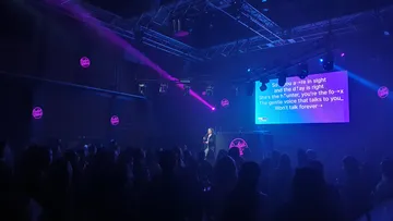 Karaoke performer on stage with projected lyrics.