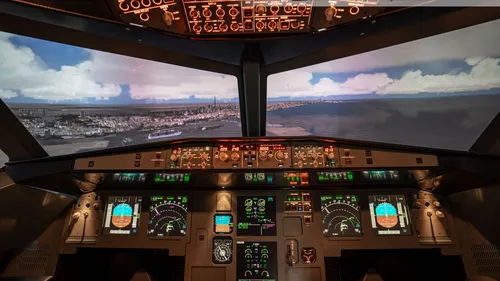 Cockpit with instruments shows simulated landing over the city.