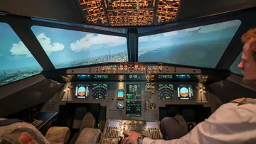 Cockpit mit Pilot steuert Flugzeug im Simulator bei Sonnenlicht.