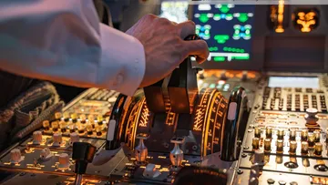 Hebel wird in einem Cockpit gesteuert, viele Instrumente sichtbar.