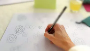 Eine Hand zeichnet geometrische Formen auf Papier.