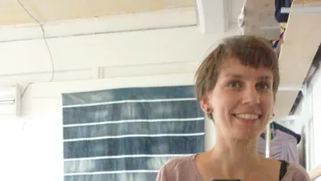 A person smiles in the mirror against a striped background.