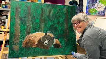Künstlerin präsentiert ein Bärenbild in einem Atelier.