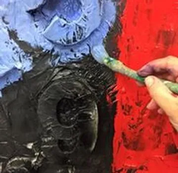 Eine Hand malt farbige Farben auf eine Leinwand.
