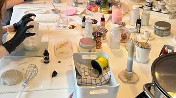 Eine Hand gießt Flüssigkeit in eine Messbecher auf einem Tisch.