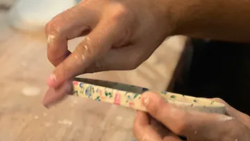 Hände halten einen farbigen Block, der bearbeitet wird.