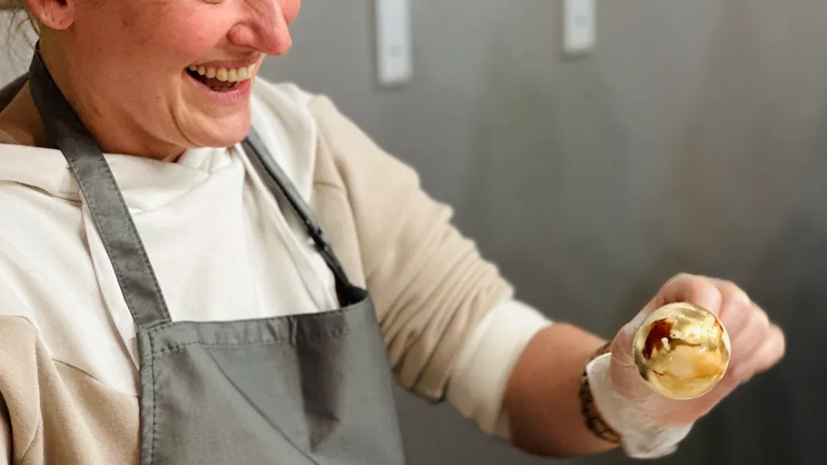 Person holding golden ice cream cone, smiling.