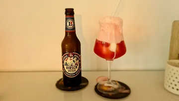 Flasche und Cocktailglas stehen auf einem Tisch.