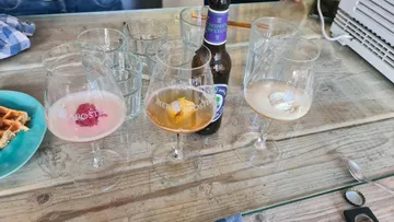 Drei Gläser mit Getränken auf einem Tisch, Snacks daneben.