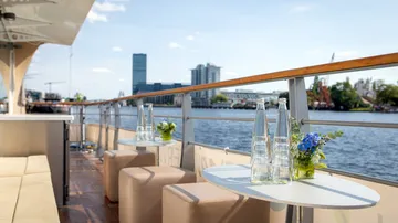 Tables with bottles of water and flowers by the water.