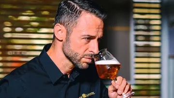 Mann riecht an einem Glas Bier in einem Restaurant.
