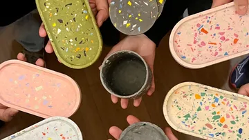 Bunte Schalen in Händen, kreativem Umfeld, gemeinsame Präsentation.