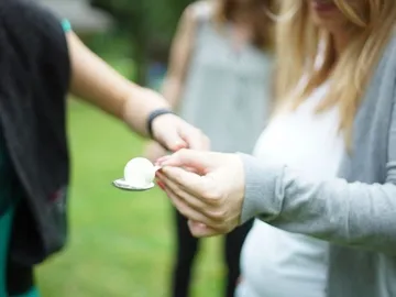 A person gives others a spoon with a ball.