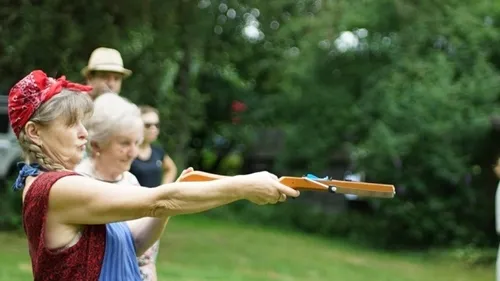 Woman aims at a meadow with wooden toys.