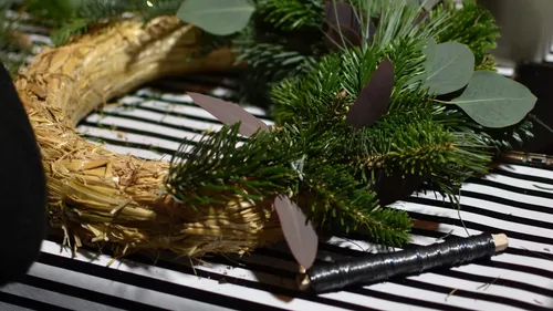 Strohkranz wird mit grünen Pflanzen und Draht dekoriert.