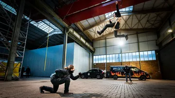 Person schwingt durch die Luft, während andere zusehen in Werkstatt.