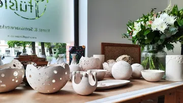 Handgefertigte Keramikschalen auf einem Tisch in der Nähe von Blumen.