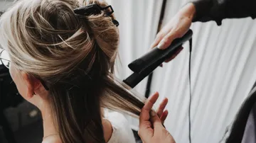 Hair is styled with a straightener in a hair salon.